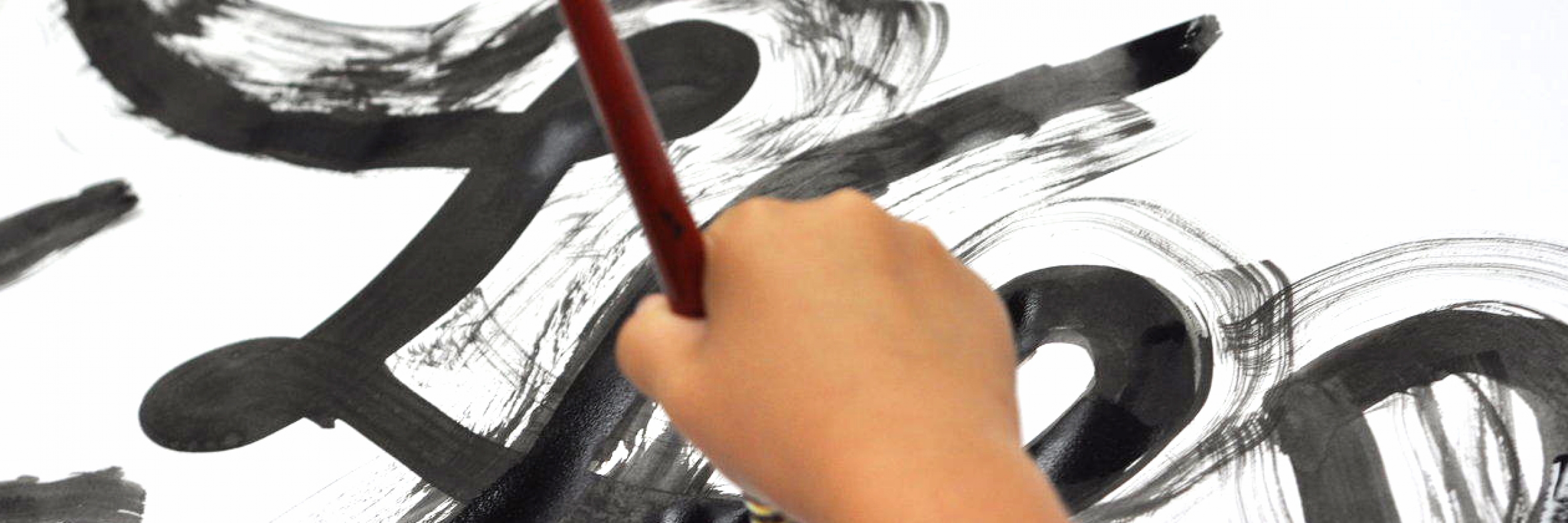 photo of a child's hand painting a black brush stroke